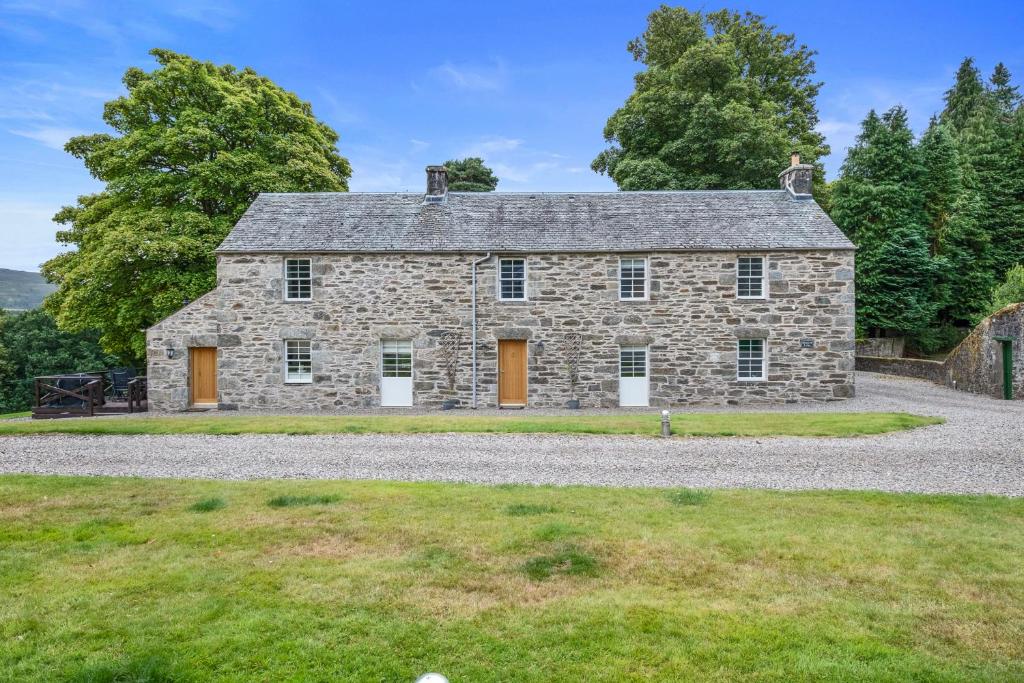 an old stone house with orange doors on a gravel road at Brandoch Lodge in Logierait