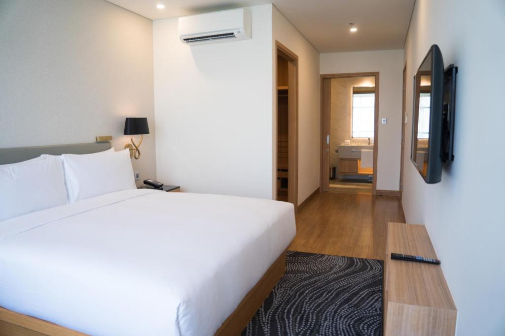 a bedroom with a large white bed and a television at Hotel Kanak in Gangānagar