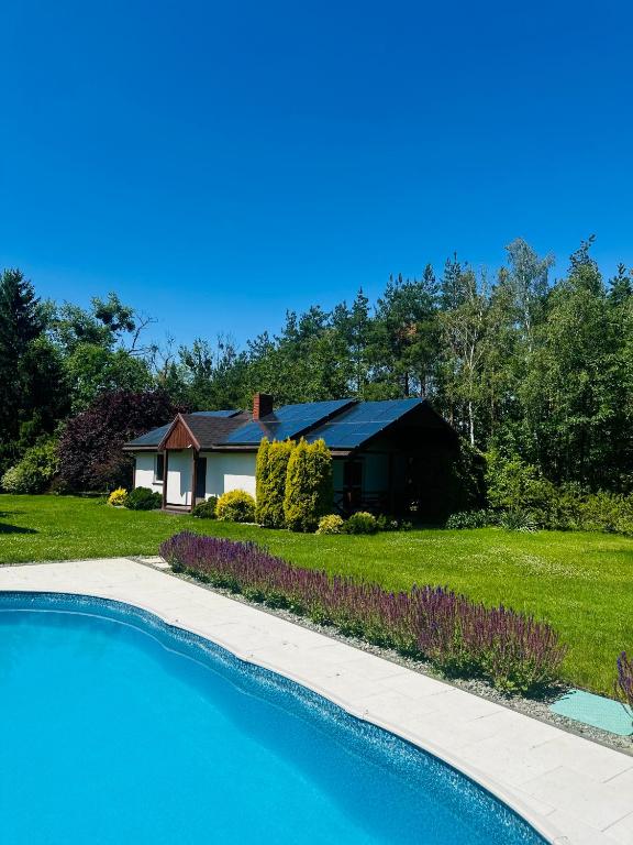 a house with a swimming pool in front of a yard at Domek na Rudzie in Ślesin