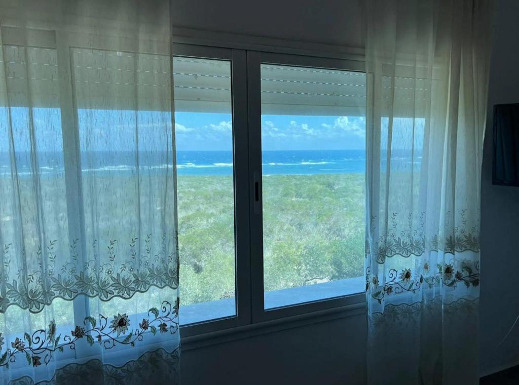 a window with a view of the ocean at Maison pieds dans l'eau in Chebba