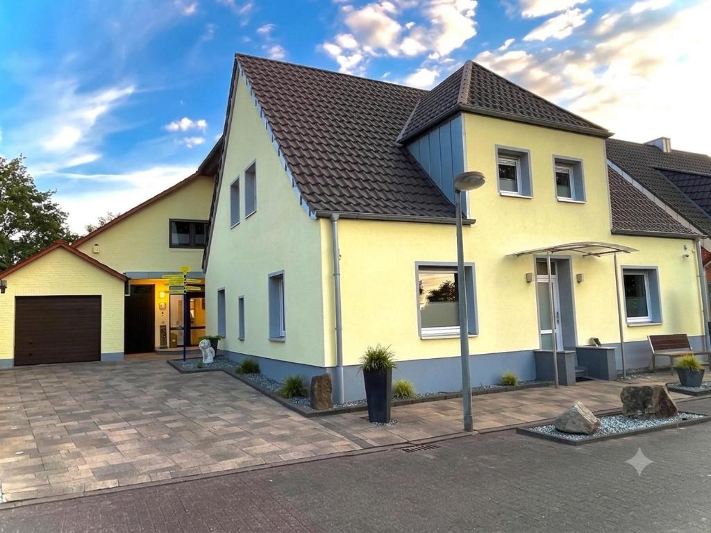 a yellow house with a black roof at Pension & Gästehaus Legden in Legden