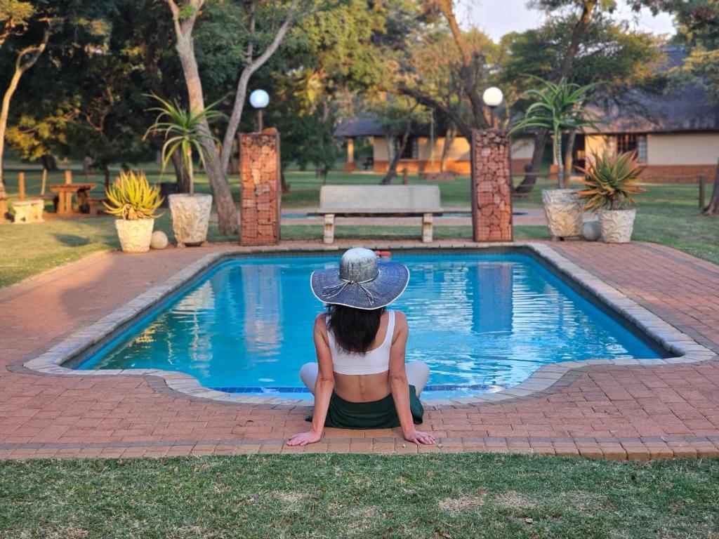 a woman sitting in front of a swimming pool at Buyskop Lodge, Conference & Spa in Bela-Bela
