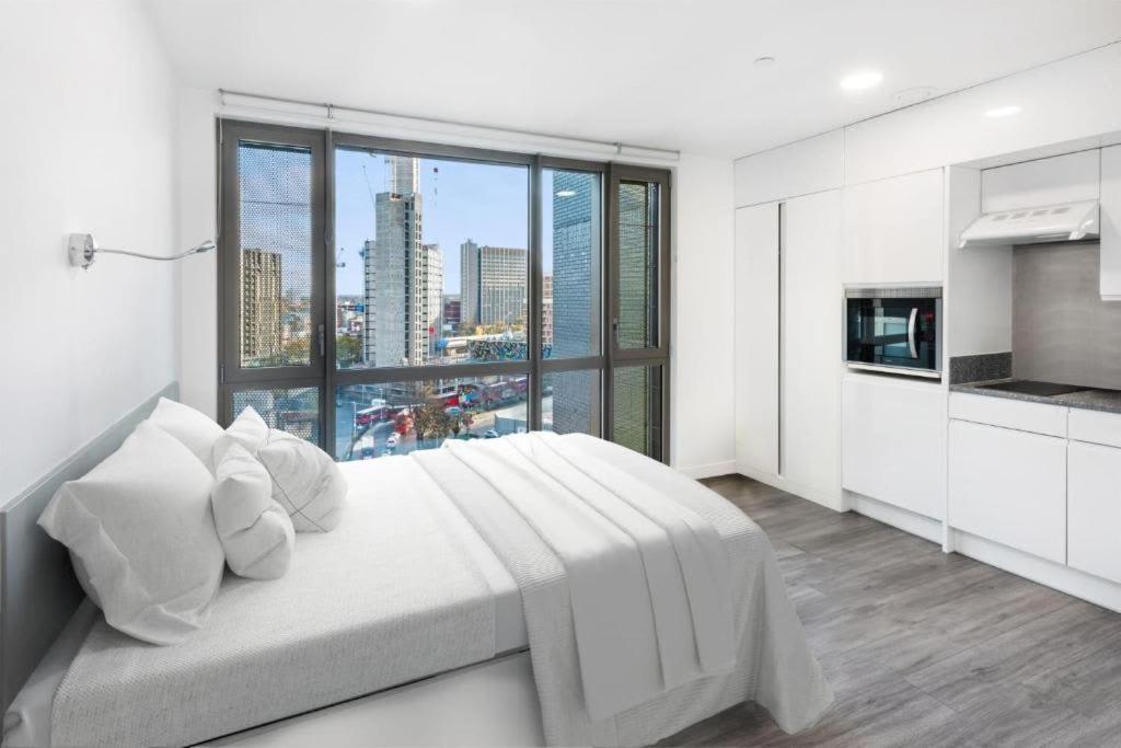 a white bedroom with a large bed and a large window at Chapter Lewisham in London in London