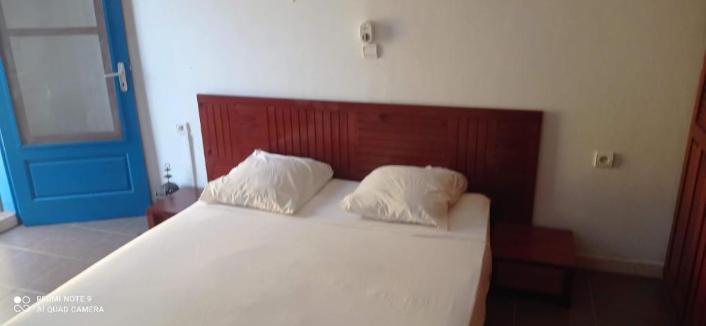 ein Schlafzimmer mit einem weißen Bett mit hölzernem Kopfteil in der Unterkunft Laduno in M'bour