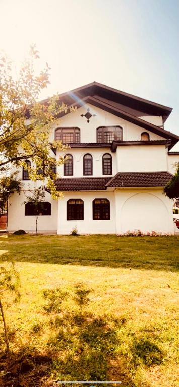 a large white building with windows on a grass field at Rahat Resort in Srinagar