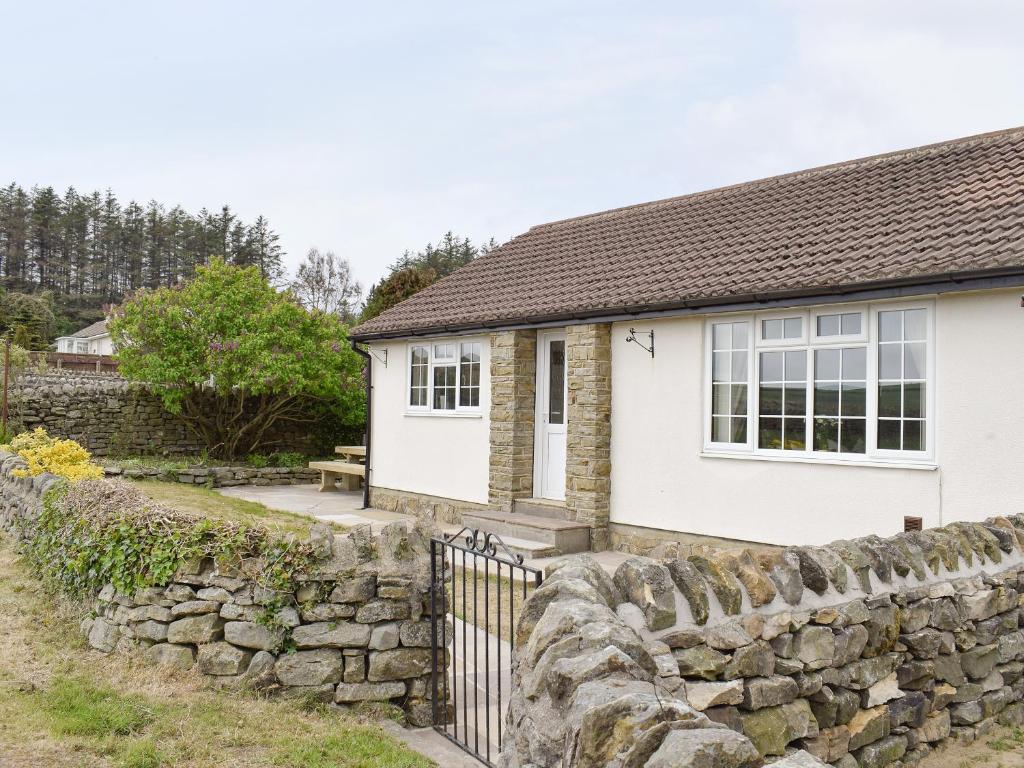 a white house with a stone wall and a fence at Rudda Farm Cottage - Uk2492 in Staintondale