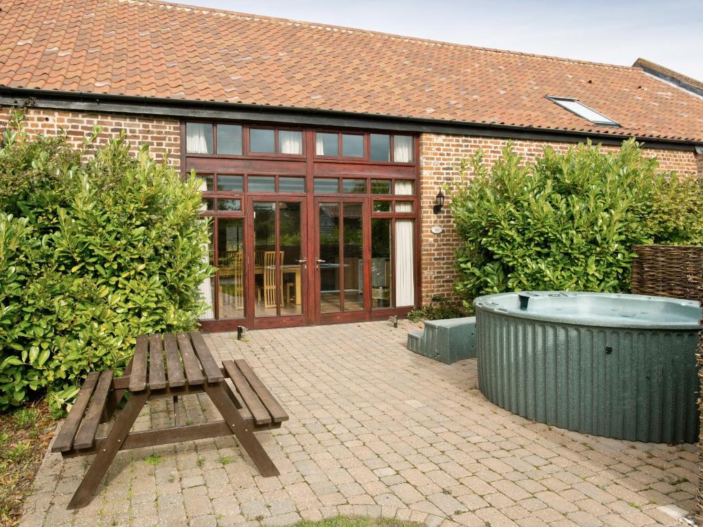a patio with a bench and a tub in front of a building at Mint - E4322 in Catfield