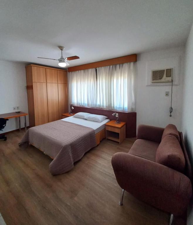 a bedroom with a bed and a couch at JK Studio centro, você merece o melhor! in Novo Hamburgo