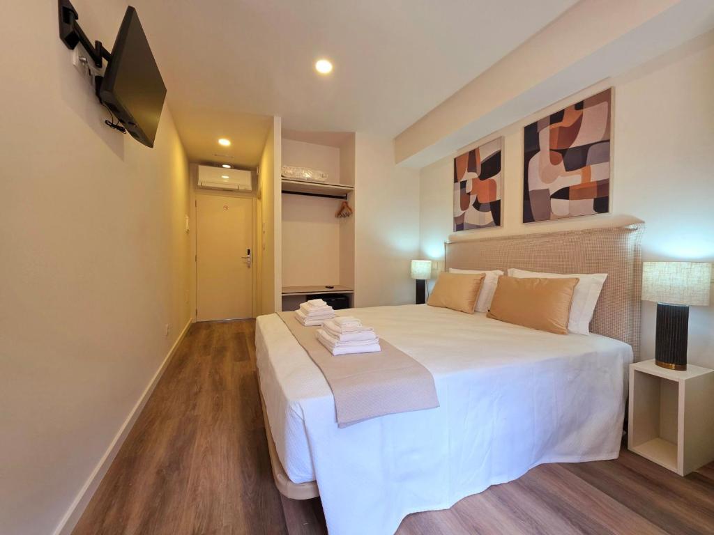 a bedroom with a large white bed and a television at AL Ponto Norte in Melgaço