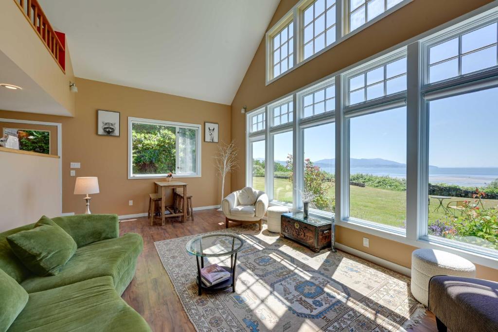 a living room with a green couch and large windows at Waterfront Bellingham Bliss: Steps to Beach! in Bellingham
