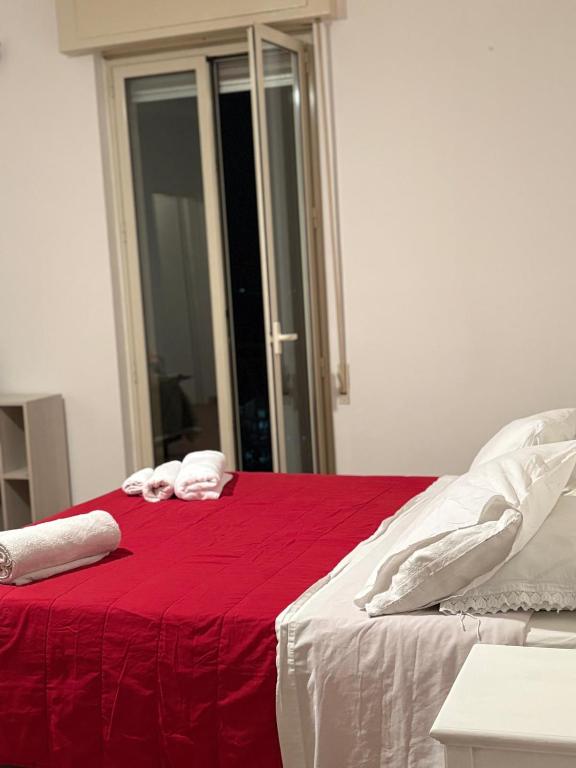 a baby laying on a bed with a red blanket at Troina rooms in Troina