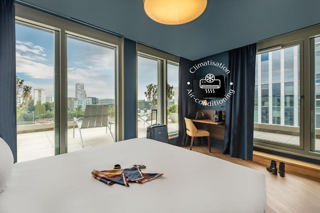 a bedroom with a bed and large windows at Hôtel de la Cité in Nantes