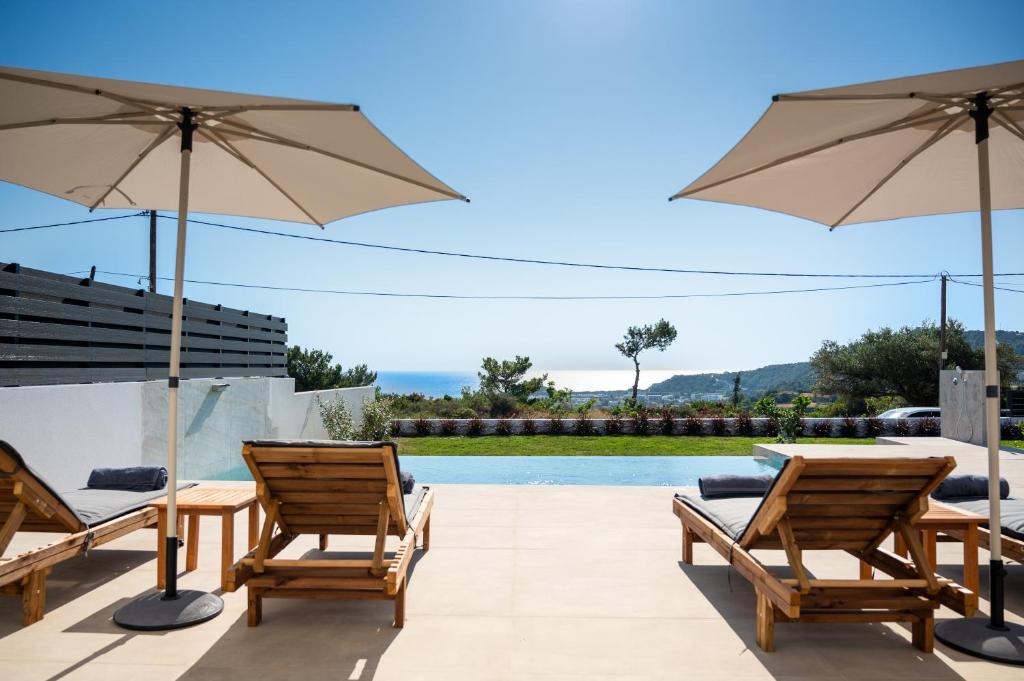 a patio with chairs and umbrellas next to a pool at Villas Pasha in Faliraki