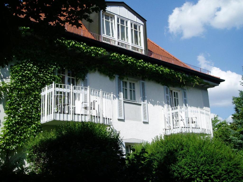 un edificio blanco con balcón y hiedra. en Villa am Schlosspark, en Múnich