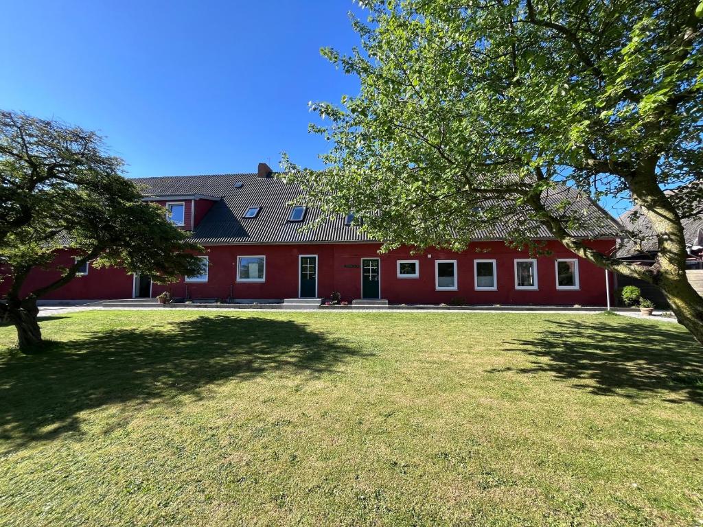 a red house with a large yard in front of it at HaRE Ferienwohnungen een in Langeneß