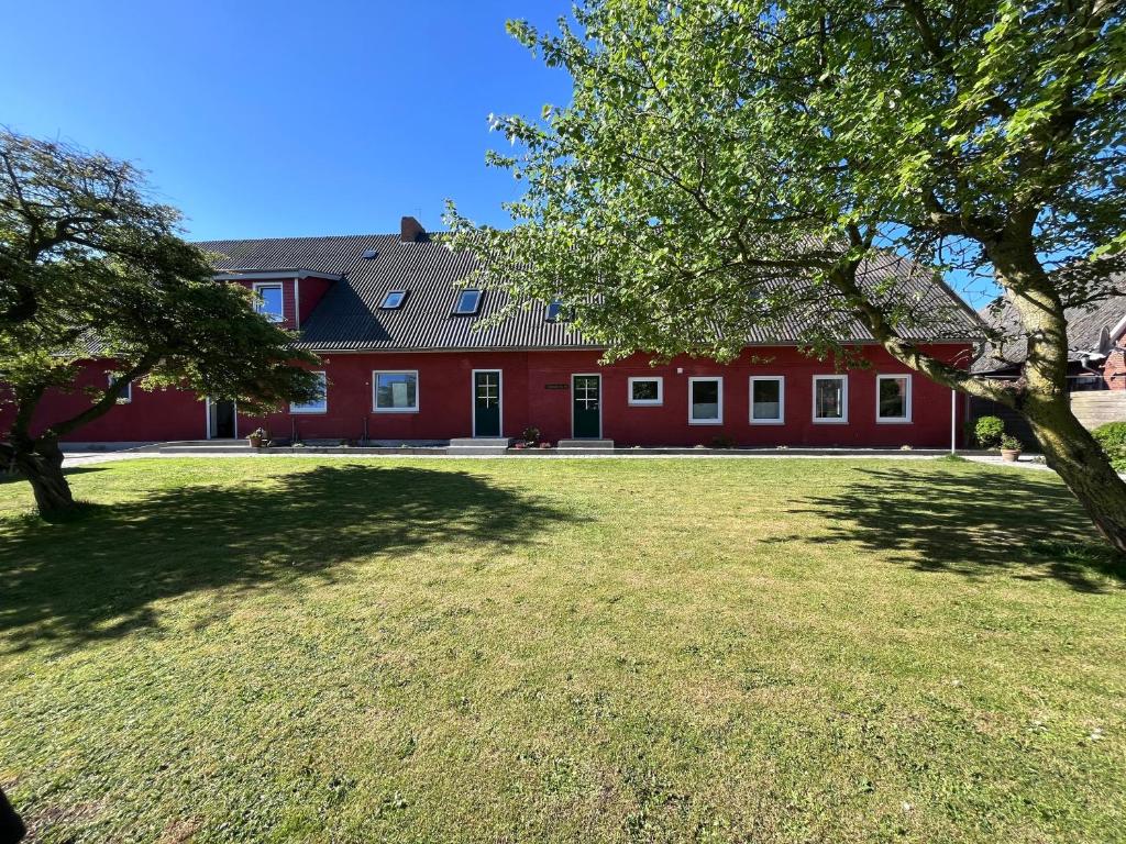 a large red building with a grass yard at HaRE Ferienwohnung DREE in Langeneß