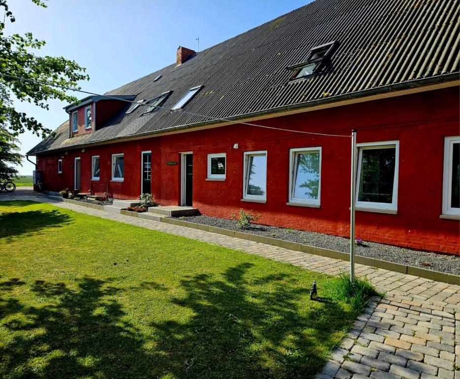 a red house with a black roof and a yard at HaRE Ferienwohnungen VEER in Langeneß