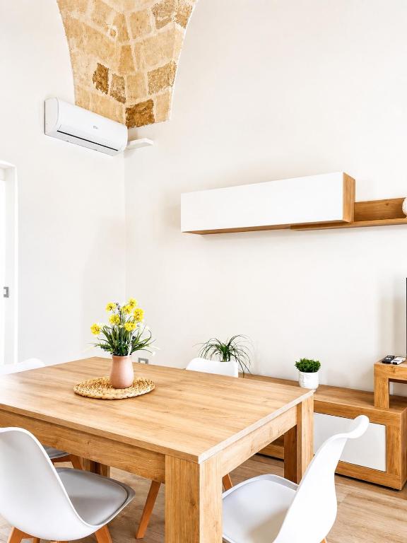 a dining room with a wooden table and white chairs at Palazzo Solera in Casarano