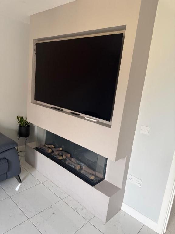 a flat screen tv above a fireplace in a living room at The Pentland Escape in Roslin