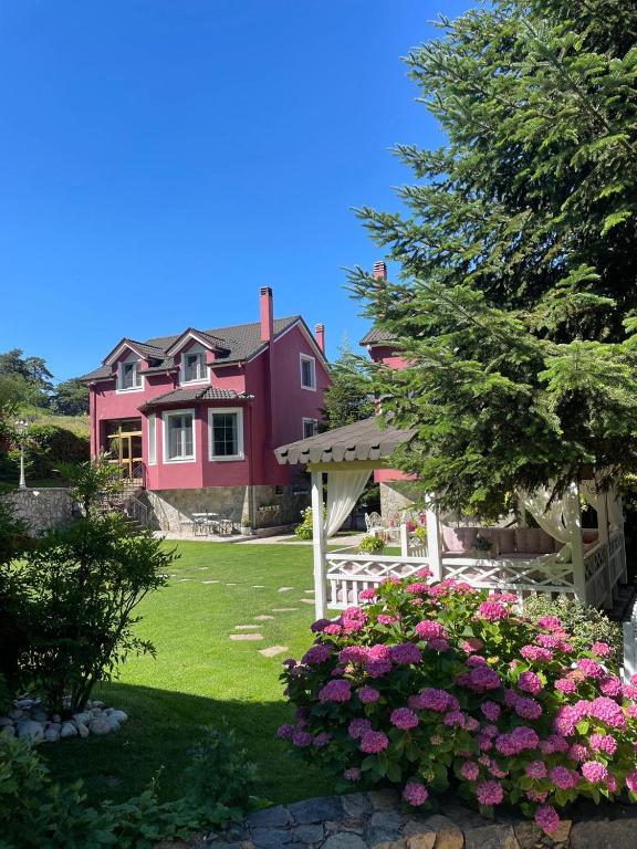 a pink house with a white fence and flowers at Tre Bujtinat Gjinar in Elbasan