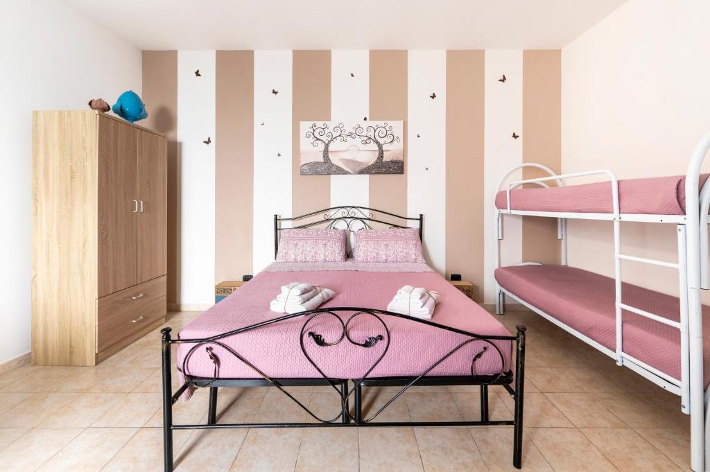 a bedroom with a pink bed and bunk beds at Lu Marchese in Minervino di Lecce