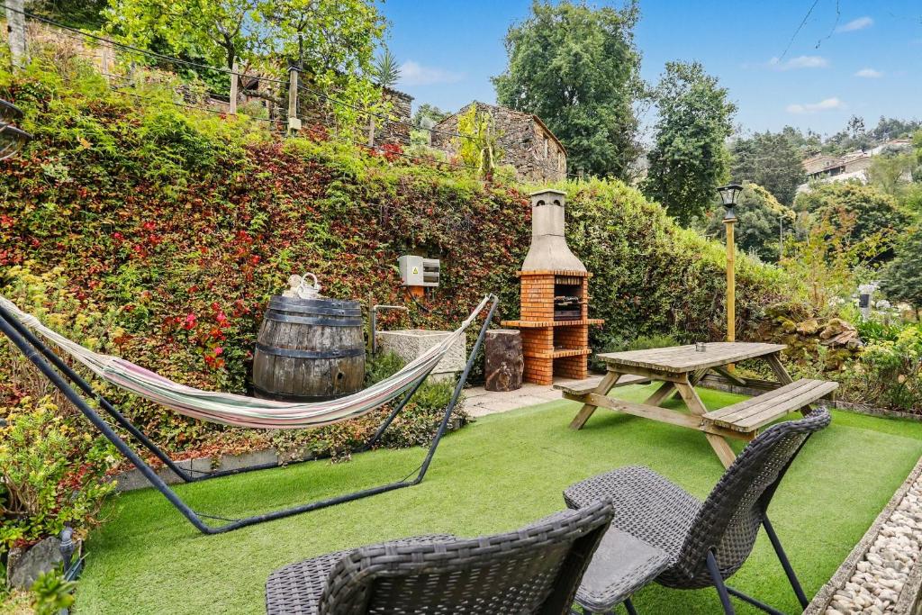 eine Hängematte, ein Tisch und Stühle in einem Garten in der Unterkunft Cantinho Do Préstimo in Águeda