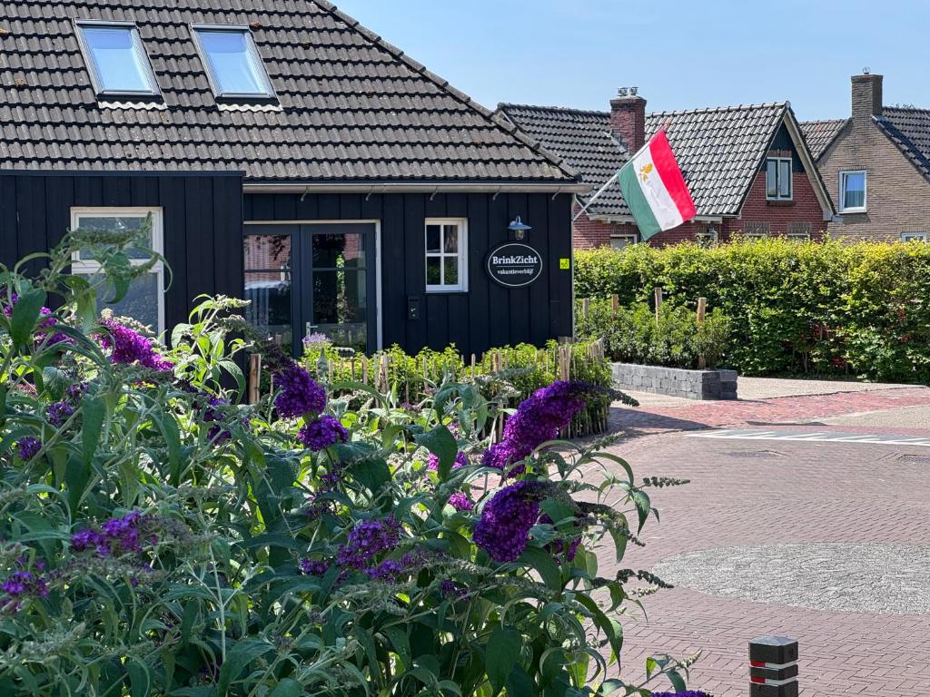 a black building with purple flowers in front of it at BrinkZicht vakantieverblijf in Peize