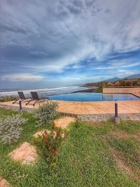 two chairs sitting next to a pool of water at Oceanfront Villa, Punta Mango in Jucuarán