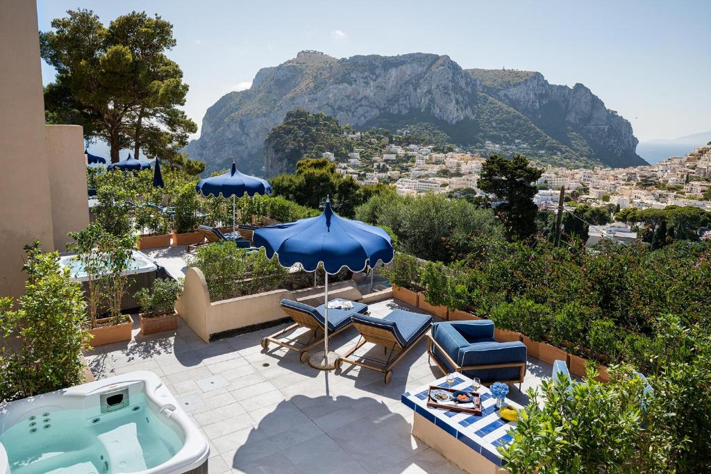 a patio with a hot tub and chairs and umbrellas at Villa Lia Hotel Capri in Capri