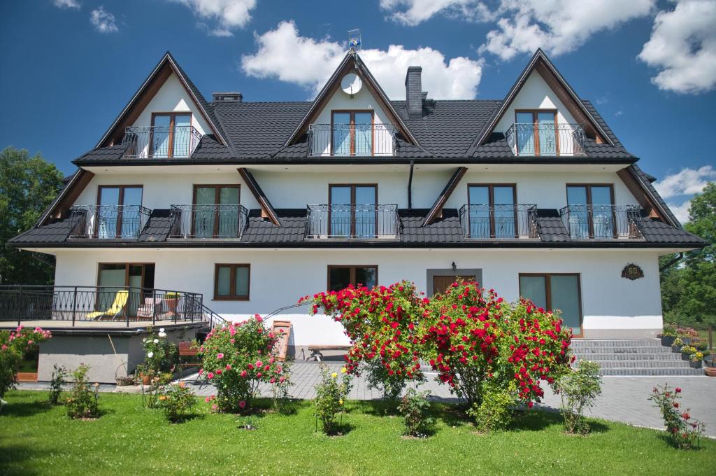 a large white house with flowers in front of it at Pokoje nad Dunajcem in Biały Dunajec