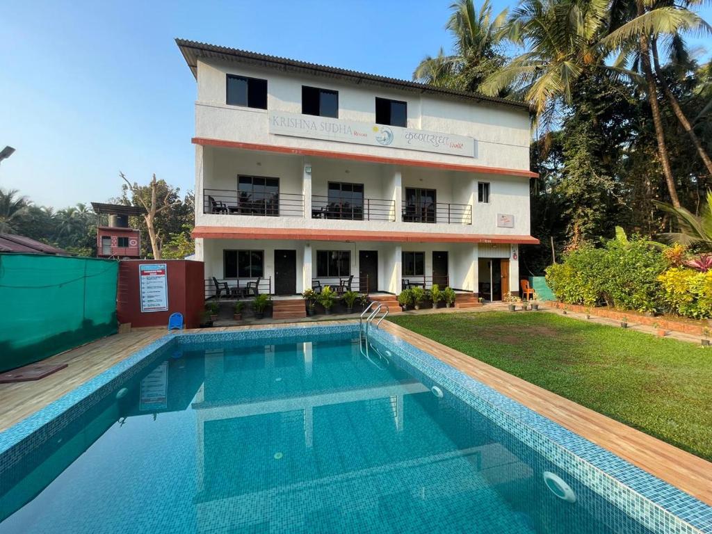 a villa with a swimming pool in front of a building at Shree Krishna Sudha Resort in Alibaug