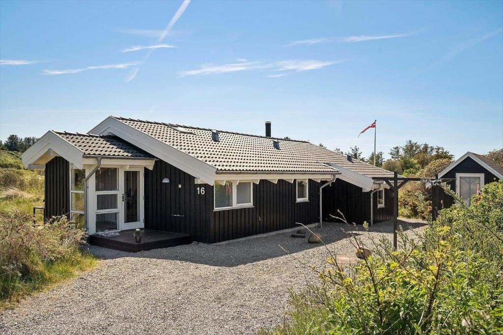 a black house with white windows on a gravel driveway at LN674-Hjorring-Rodspaettevej-16 in Hjørring