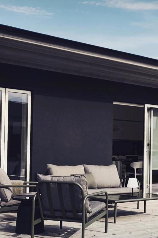 a patio with a couch and chairs on a building at Vila Karup Modern Scandinavian Holiday Home in Båstad