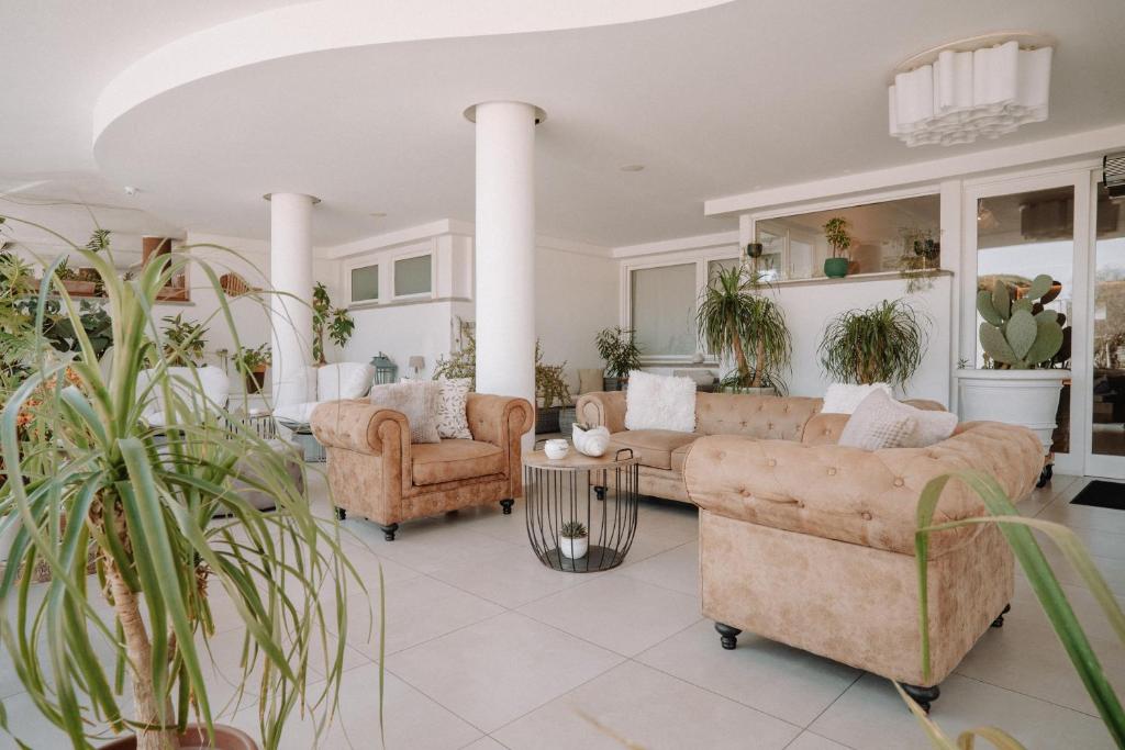 a living room with couches and chairs and plants at Lula Hotel - Ex Love & Fama Hotel in Sabaudia