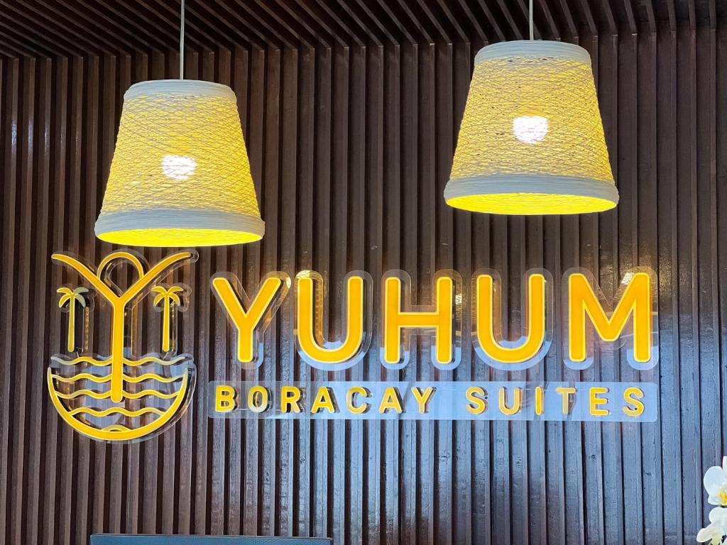 two lights hanging from a sign in front of a yellow sign at Yuhum Boracay Suites in Boracay