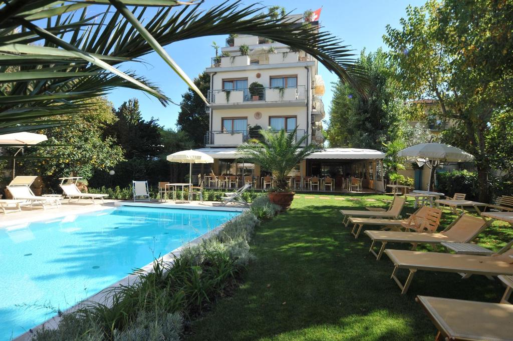 a hotel with a pool and chairs and a building at Hotel Bacco in Lido di Camaiore