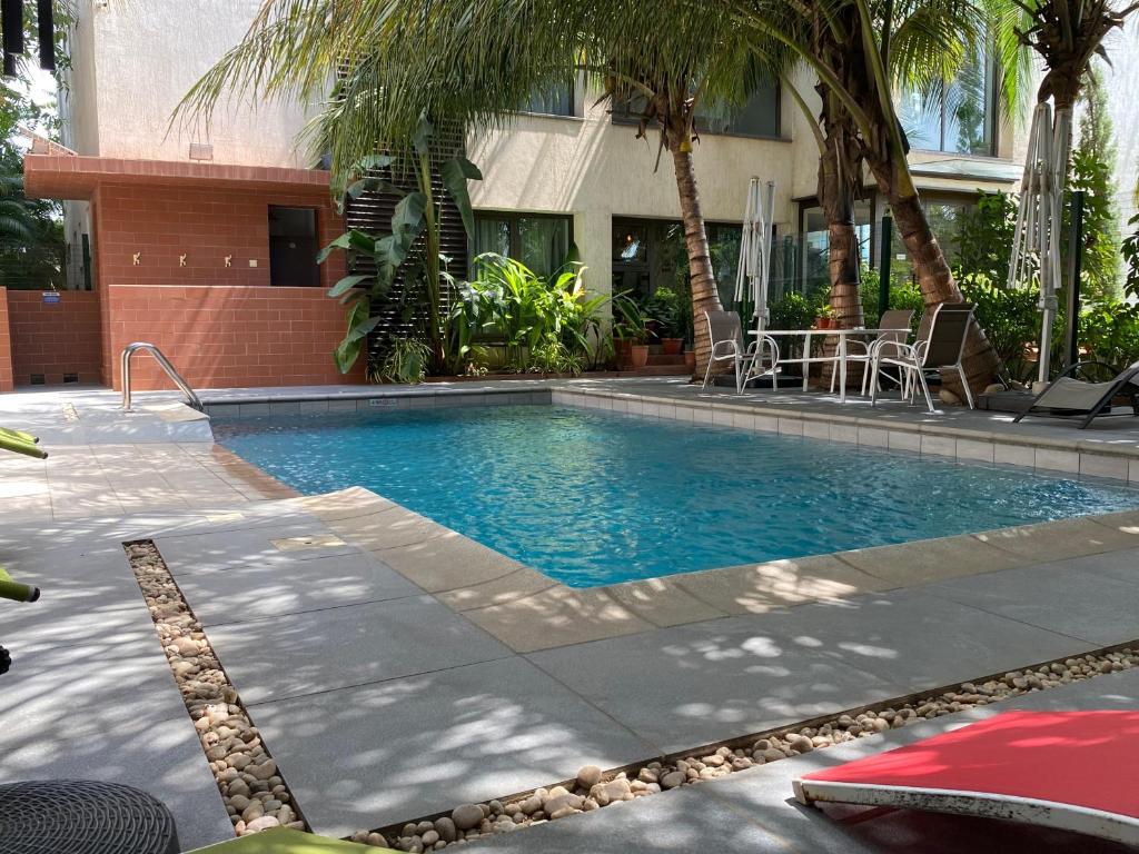 a swimming pool in front of a building with palm trees at Casa Bianca in Accra