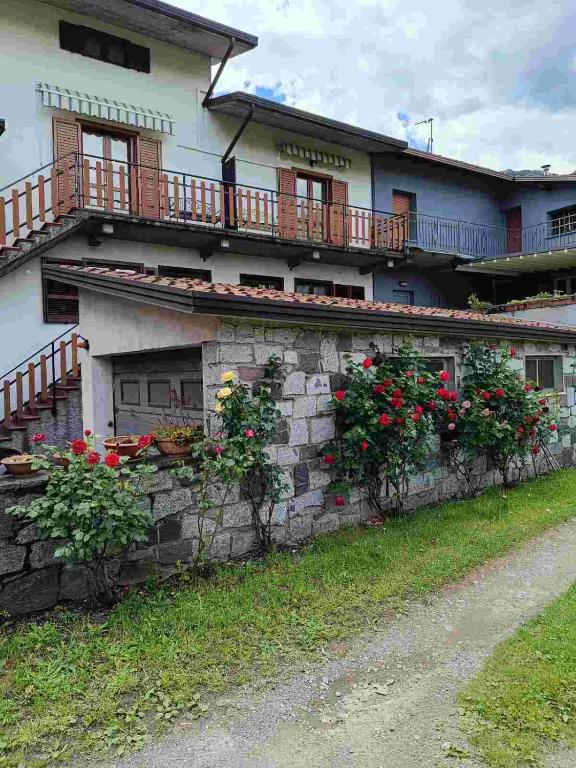 a house with flowers on a stone wall at Locazione breve LE ROSE in Darfo