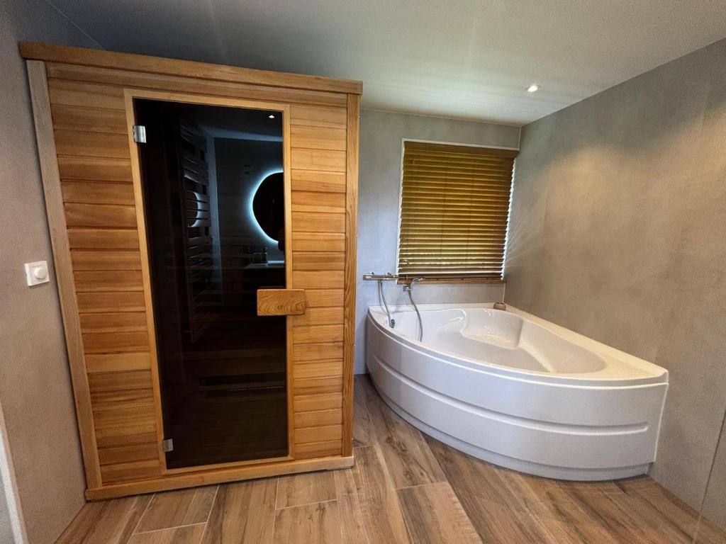 a large white tub in a bathroom with a window at Zilt en Zen Zeeland in Bruinisse