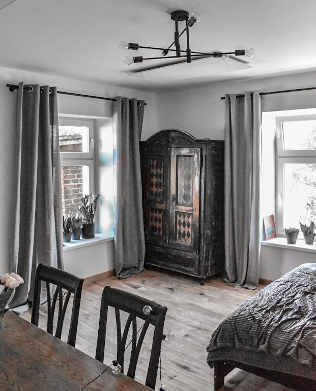 a bedroom with a bed and a table and two windows at Apartament Antracytowe Wrota 3 in Boguszów-Gorce