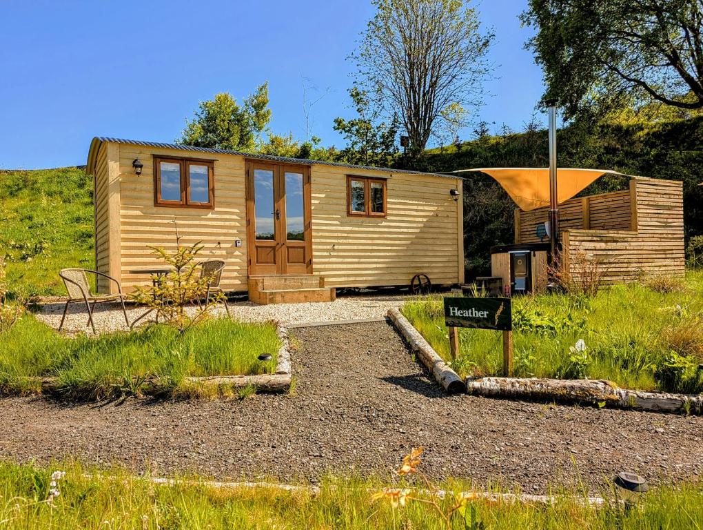a small cabin with a sign in front of it at Lintmill Lodges - Heather Shepherds Hut in Sorn