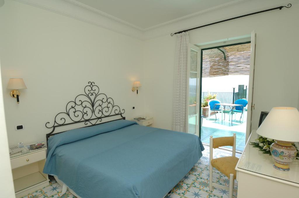 a bedroom with a blue bed and a sliding glass door at Hotel Aurora in Amalfi