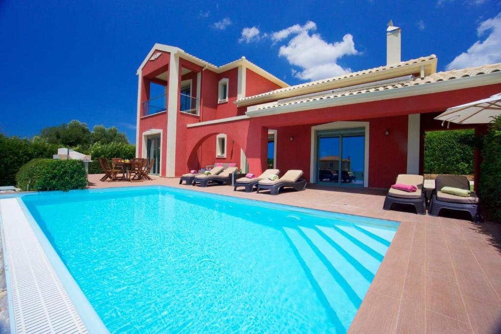 a villa with a swimming pool in front of a house at Trapezaki Queen Villa in Trapezaki