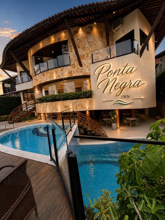 a hotel with a swimming pool in front of a building at Divi-Divi Praia Hotel in Natal
