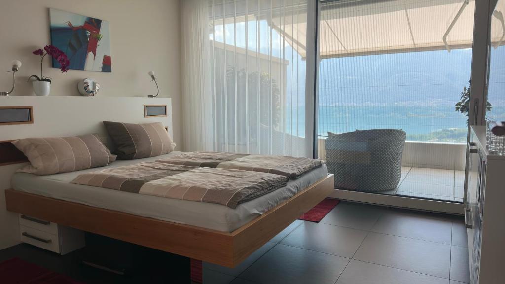 a bedroom with a large bed and a large window at Room Casa Jessika in Orselina