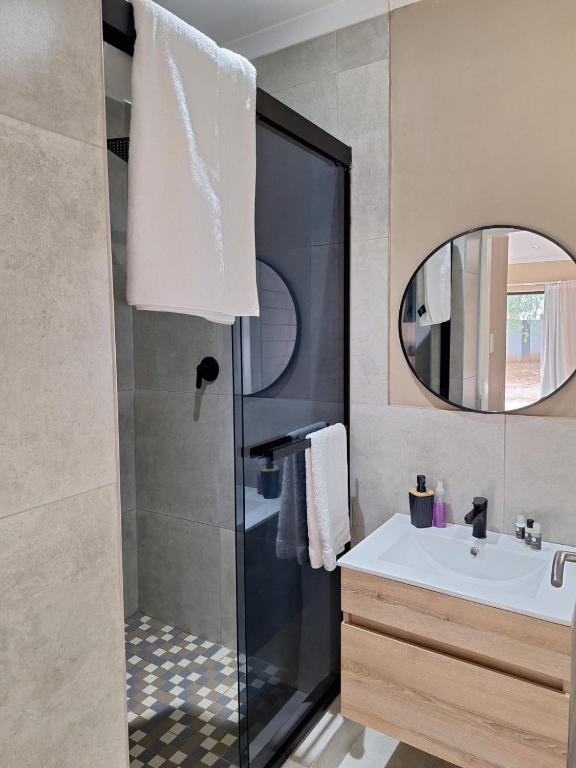 a bathroom with a shower and a sink and a mirror at 49 Sannaspos in Bloemfontein