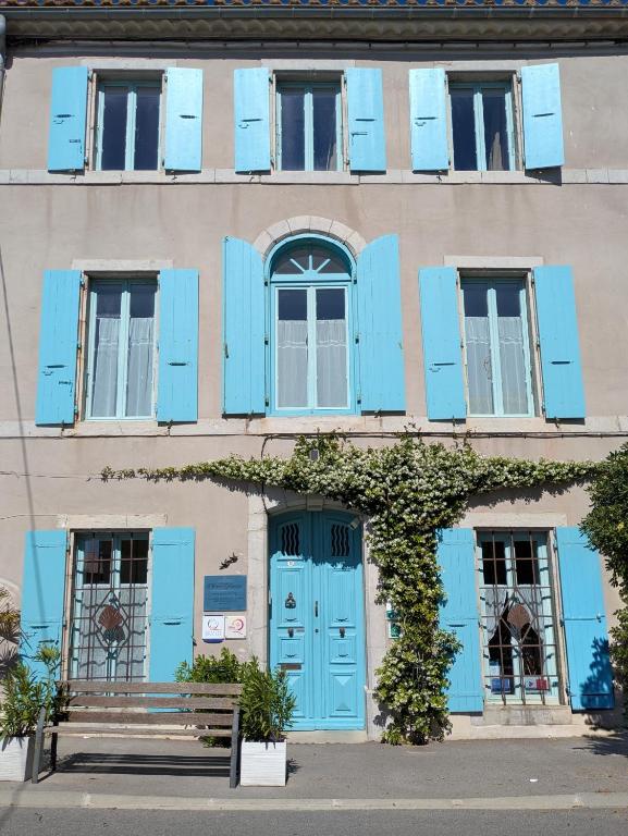 a building with blue shutters and a bench in front at Alcôve Marine in Gruissan