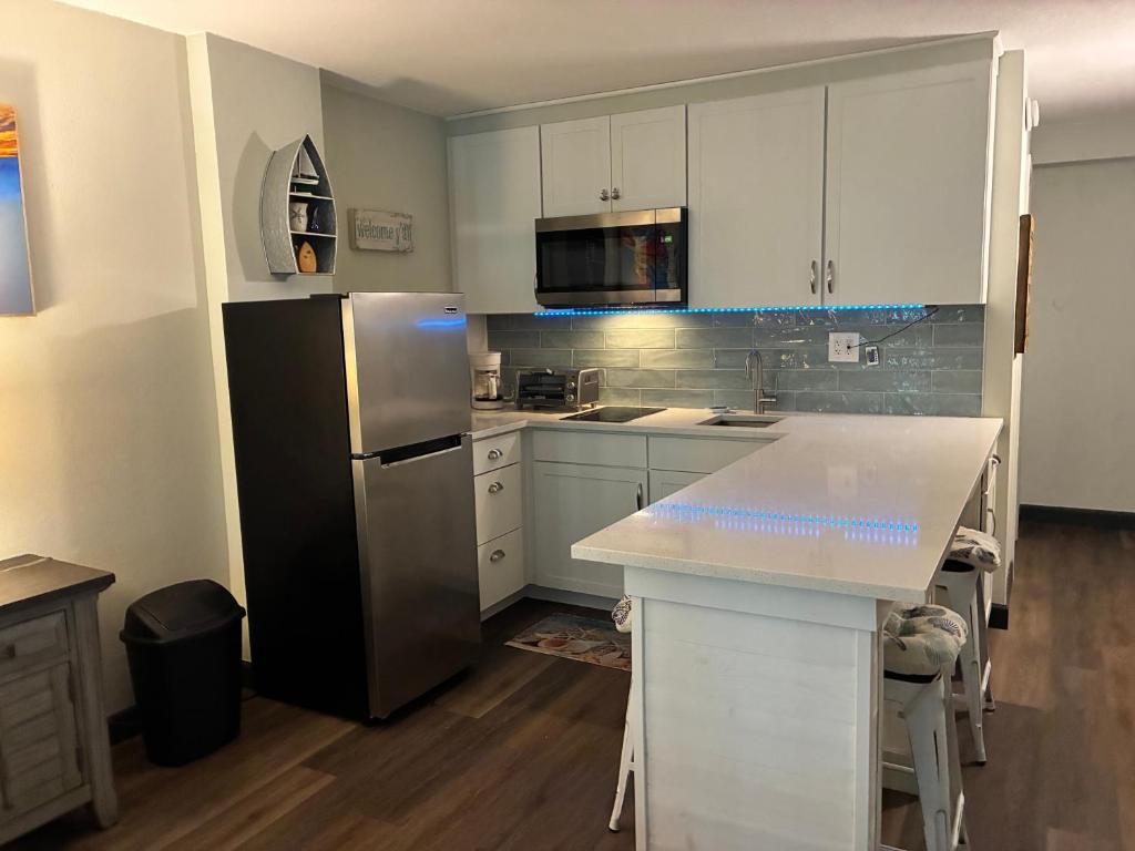 a kitchen with white cabinets and a black refrigerator at Oceanside Inn in Daytona Beach