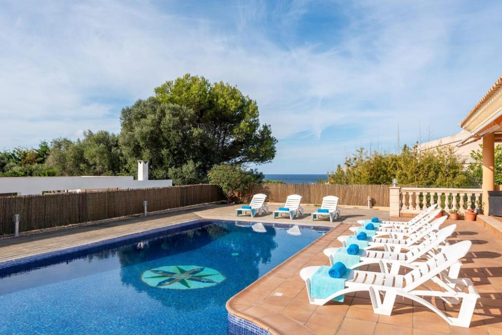a swimming pool with lounge chairs and a swimming pool at Villa Dori by Villa Select in Punta Prima