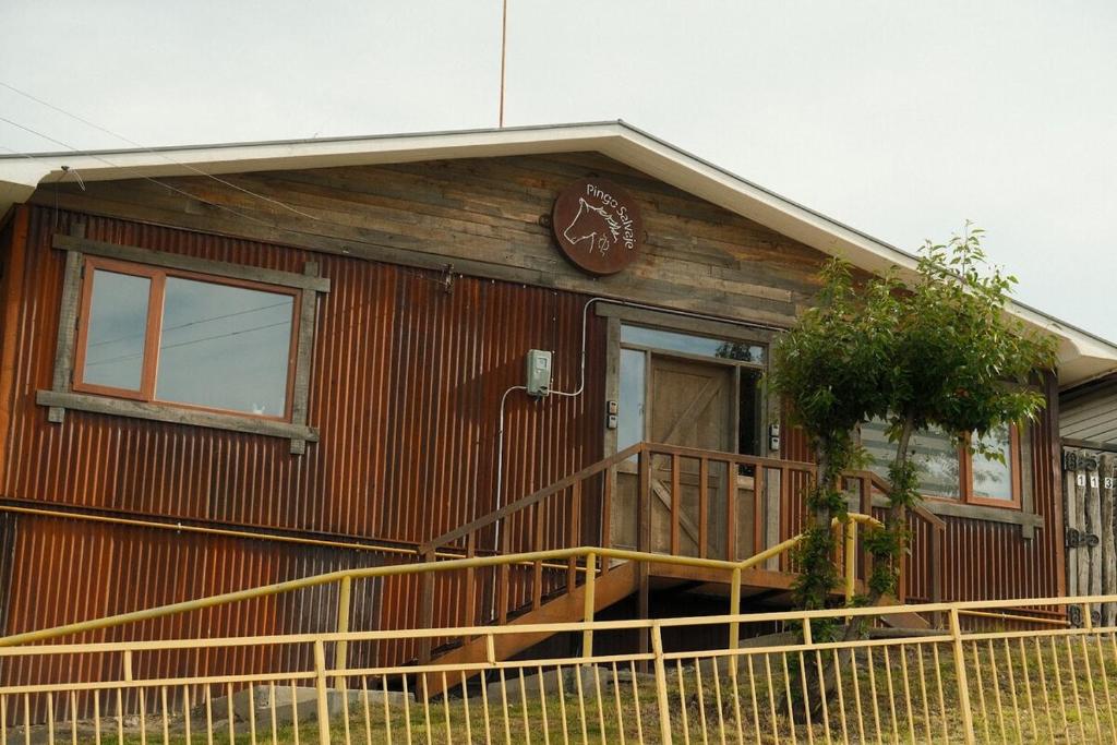 a small wooden house with a porch and a door at Casa Oxidada in Puerto Natales